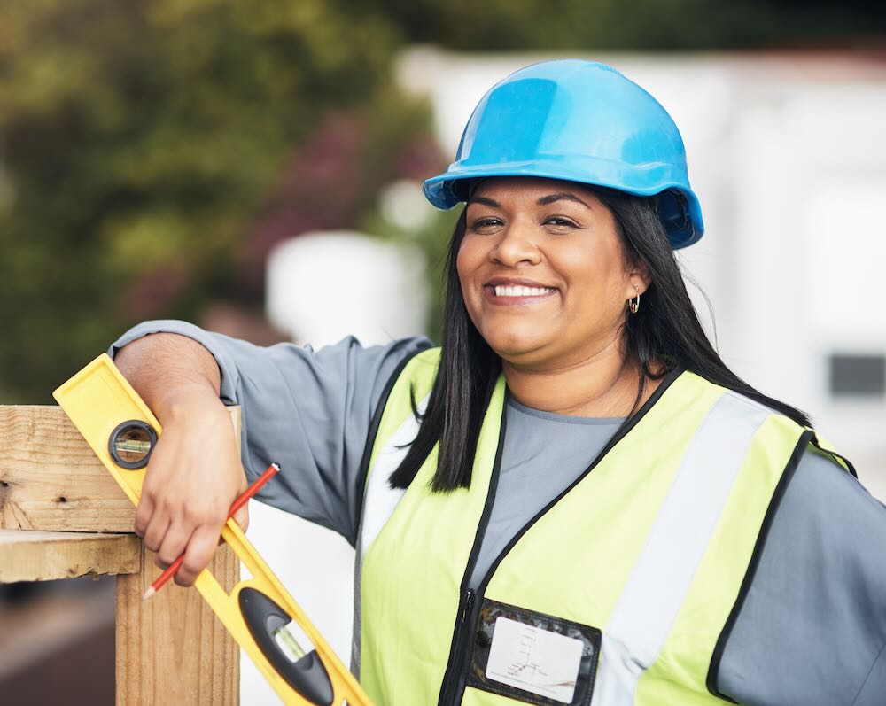 Cropped portrait of a young female construction worker smiling at a camera. 