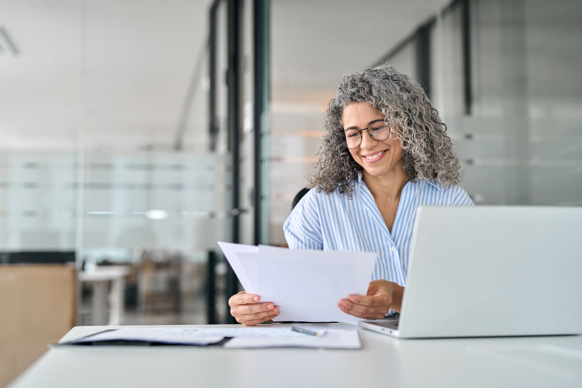 Mature woman working with documents at her desk smiling